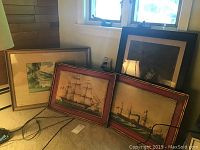 Image showing three framed artworks leaning against wall; includes original watercolor and two framed prints featuring ships.