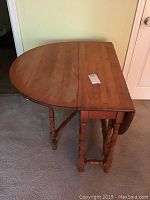 Full view of the drop leaf gate leg table with both leaves extended, showing rounded tabletop edge and turned legs.