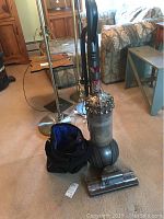 Full view of the Dyson Big Ball vacuum with ball base, clear dust bin, and accessory bag placed next to it on carpet