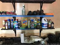 Shelves with assorted household liquid cleaners and sprays including Clorox bleach, Mr. Clean, SOS cleanser, furniture polish, and other cleaning products.