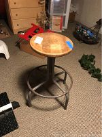 Vintage wood and metal stool with round wooden seat and metal base shown in a carpeted room.