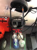 Full view of CleanForce pressure washer with hose and wand, and four bottles of cleaning liquids in front
