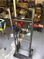 Full view of the Angelus hand truck standing on a concrete floor with various tools and storage in the background.