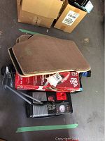 Photo showing brown and tan fabric car floor mats stacked on top of boxed vacuum and accessories.