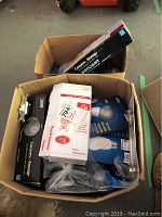 Two open boxes showing multiple Cree light bulb packages, some electrical switches and wiring, and a metal door handle.