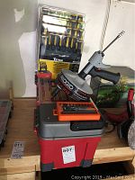 Photo shows assembled lot items including Ridgid autofeed trigger, Titan screwdriver set in packaging, HDX driver set, all placed on top of the red Keter tool box.