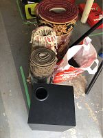 Three rolled rugs and KLH subwoofer on floor
