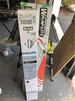 Boxes of Philips Cool White Alto II F32T8 TL841 fluorescent bulbs and Lithuania Lighting Wrap Lite Model 3348 T8 lamps standing upright in garage.