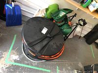 Electric leaf shredder with collection bag and Scotts Handy Green spreader in background