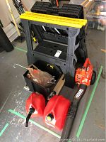 Photo of sawhorses stacked with black plastic bin, red gas canisters, and Yamabiko Echo PB250LN blower