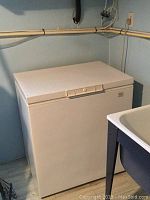 Closed white chest freezer, showing dimensions and white exterior.