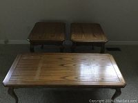 Photo shows two square oak side tables and one rectangular oak coffee table arranged on floor in front of wall.