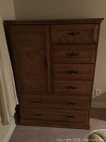Front view of the oak patterned armoire with drawers and door visible
