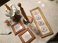 Photo showing crystal and brass candle holders, wooden paper towel holder, floral kitchen cups on stand, framed floral pictures, and framed tea cup prints.