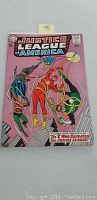Front cover of Justice League of America #27 comic book from April 1964. Shows colorful superhero characters and comic title. Sticker with '45' on top.