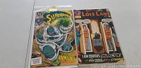 Front covers of Superman the Man of Steel #18 and Lois Lane #106 comics side by side on table.