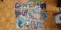 Top view of 14 Spiderman and Marvel related comic books laid out on wooden floor showing condition and cover art.
