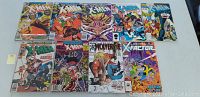 Front view of 9 Marvel comic books laid out side by side, showing covers with various characters and titles including X-Men, Wolverine, X-Factor, and more. Shows condition with visible wear and damage.