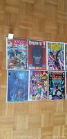 Photo of 6 comic books laid out on a wooden floor showing X-Men, Magneto, and others.