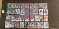 Photo showing 36 hockey cards in protective sleeves arranged on a dark surface. Mostly numbered rookie and insert cards visible.