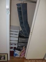 Closet view showing hanging fabric shoe holder, plastic storage drawers, and clothes hangers.