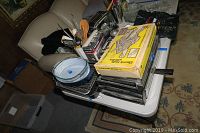 Overview of all kitchenware items stacked on a table including utensils, baking dishes, and small appliances