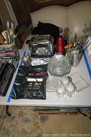 Overview of kitchenware items including Hamilton Beach toaster, bar utensils, glassware, and plates arranged on a table.