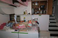 Overview of basement laundry area showing various textiles, boxes, plastic containers, and household items on top of washer and dryer