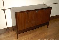 Front side view of dark mahogany Lexington Galaxy buffet cabinet with closed doors, four chrome handles visible, standing on tapered legs on wood floor under white panel wall.