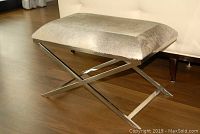 Side profile of bench showing chrome X-base and hide-upholstered seat
