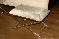 Angled view showing hair-on-hide upholstered top and chrome X-base
