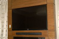 Front view of 60" Sharp Aquos TV mounted on wood panel above fireplace