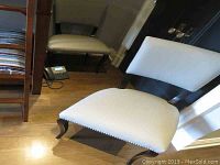 Pair of cream/off-white upholstered accent chairs with wooden curved frames and silver nailhead trim seen from multiple angles