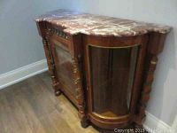 Front perspective of entire wooden cabinet showing red marble top and decorative front
