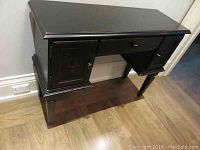 Full view of the stained wooden desk showing flat top, one center drawer, and two side cabinets with doors.