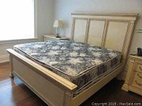 Full side view of king size bed frame with mattress showing cream painted headboard and footboard