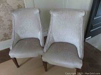 Front view of two beige upholstered occasional chairs positioned side by side