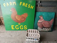 Photo showing two farm-themed wooden signs and a portion of the stacked egg cartons