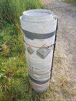 Rolled-up large pool shell or liner support material secured with duct tape and rope, likely part of the above ground pool structure.