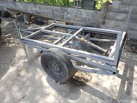Side-angle view of the steel trailer frame showing axle, tire and coupler