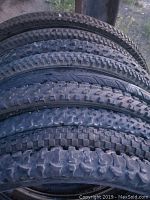 Photo showing stacked side view of bicycle tires showcasing varying tread patterns and thicknesses.