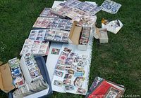 Full view of boxes, binders, and stacks of sports cards arranged on outdoor surface.