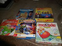 Photo of lot containing five board games: Connect Four, Battleship, Monopoly Junior, Glee, and For Men Only, boxes all visible on table surface.