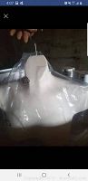 White mannequin shoulder hanger with metal hook wrapped in plastic, hanging from a hand.