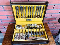 Wide shot of wooden chest open showing all silver-plated flatware pieces.
