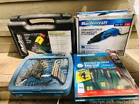 Photo showing a black carrying case for QuikDrive drill attachment, Mastercraft rotary tool kit box, blue Allen wrench set case, and a packaged plier set on stairs.