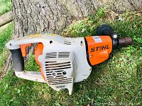 Side view of entire unit on grass showing body, recoil starter housing and drill chuck.