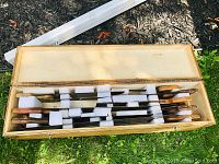 Top view of open wooden box fitted with foam padding and containing multiple hand saws with wooden handles.