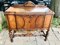 Front view of the antique wooden sideboard with decorative carvings and polished finish.
