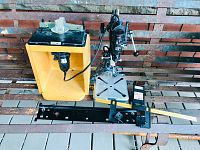 Full view of two router table units with Dremel rotary tools, one wooden base and one metal drill press style.